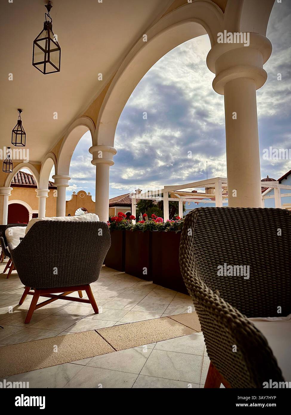 This image features a cozy outdoor seating area beneath a charming archway, showcasing the elegant design of a resort. The setting includes stylish wi - Smartphone Captured Stock Image