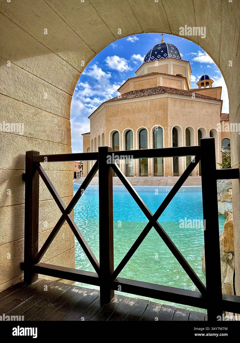This stunning image captures an elegant archway framing a serene view of a resort pool and a magnificent dome-shaped building. The crystal-clear water - Smartphone Captured Stock Image
