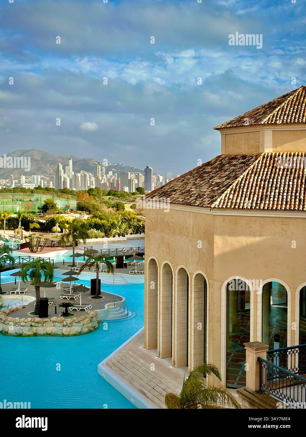 This stunning image captures the serene beauty of a luxury resort, featuring a crystal-clear pool with unique island features surrounded by palm trees - Smartphone Captured Stock Image
