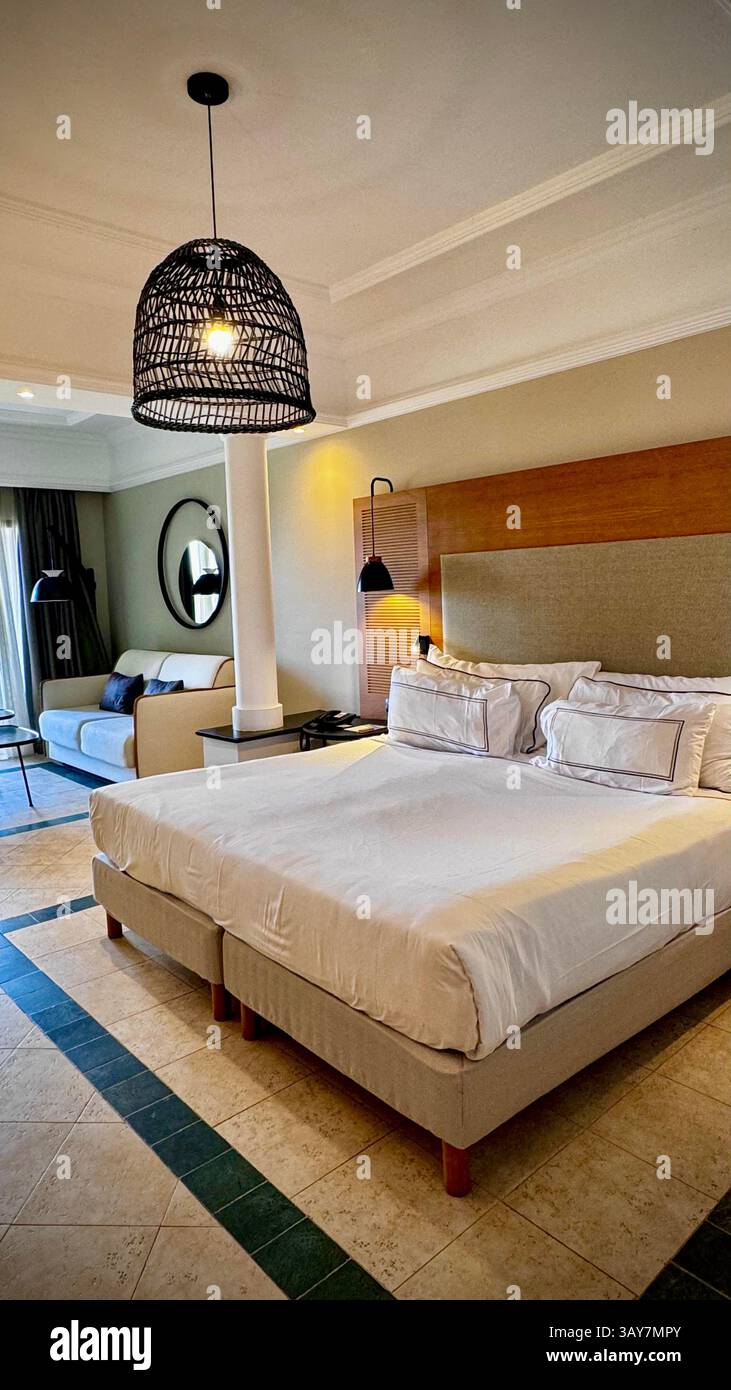 This image captures a stylish hotel room that exudes modern elegance and comfort. The spacious bedroom features a large, comfortable bed with soft, cr - Smartphone Captured Stock Image