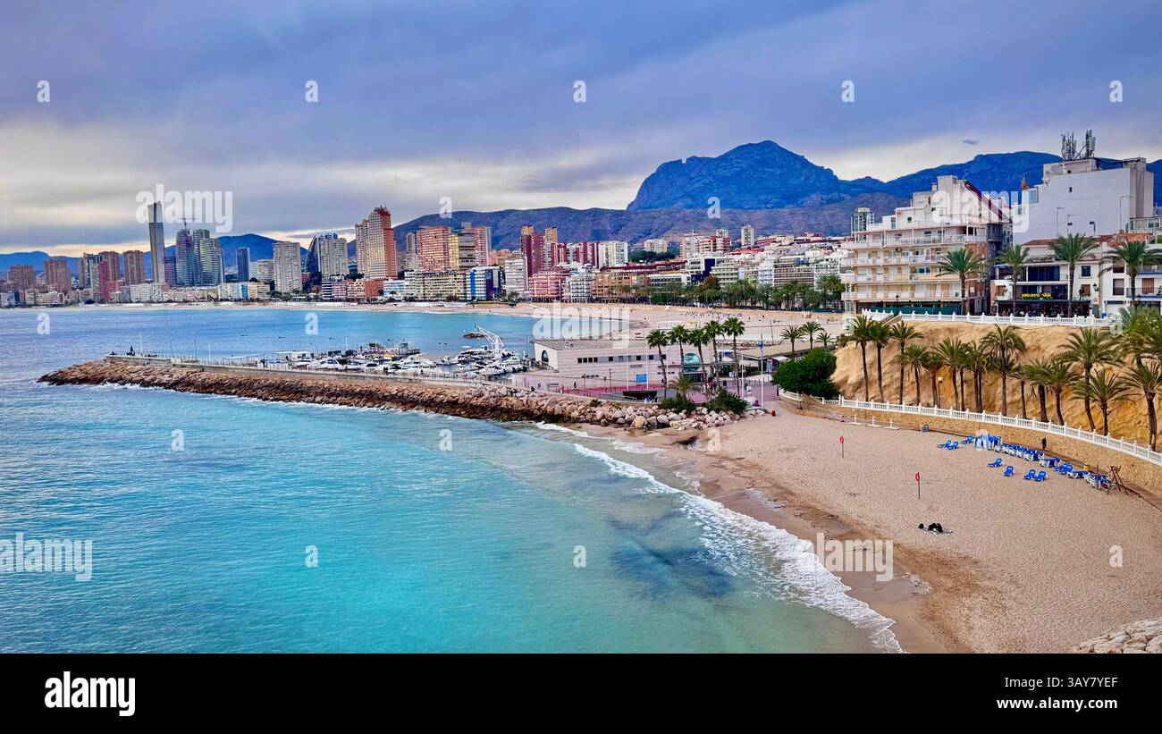 This photo captures a beautiful view of a coastal city, showcasing the skyline along the sandy beach and the crystal-clear Mediterranean sea. The palm - Smartphone Captured Stock Image
