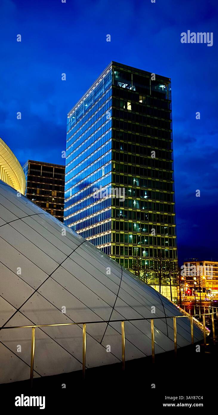 Modern glass skyscrapers and urban structures glowing under a deep blue night sky in Luxembourg City. A sleek and illuminated business district showca - Smartphone Captured Stock Image