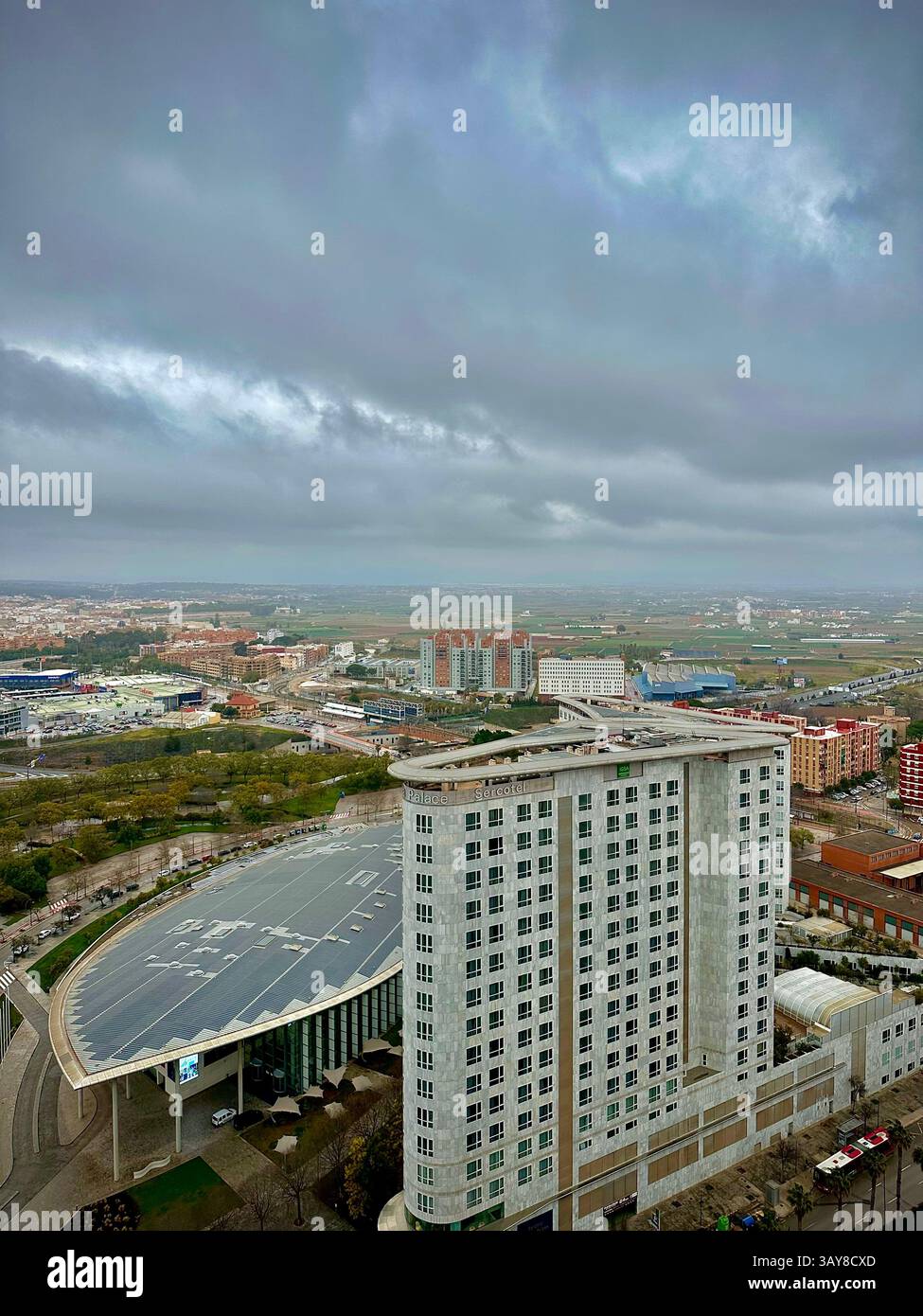 A wide aerial perspective of Valencia's suburbs and modern hotel structures under cloudy skies. - Smartphone Captured Stock Image