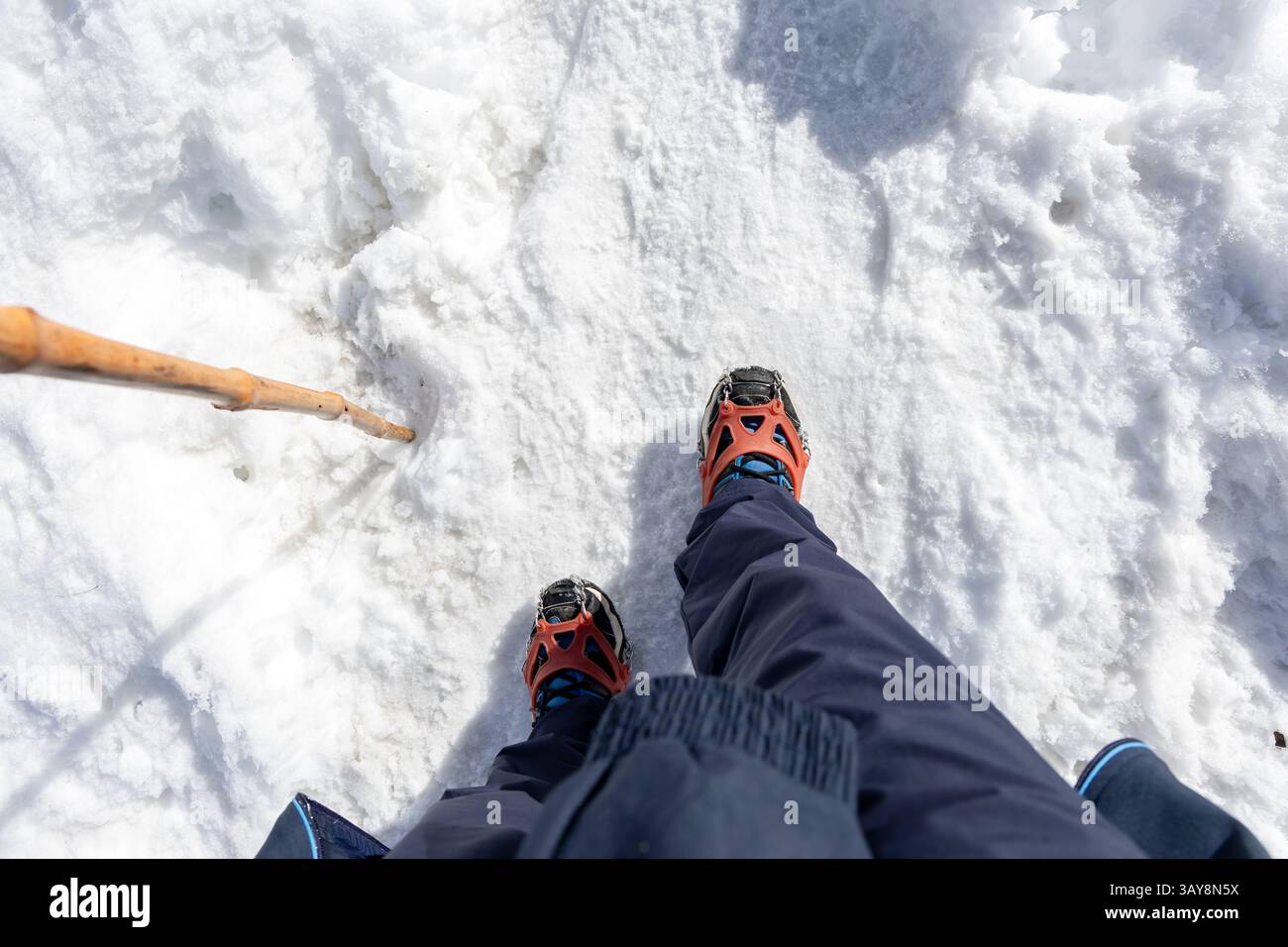 man waking on snow with shoe crampons and stick at day Stock Photo