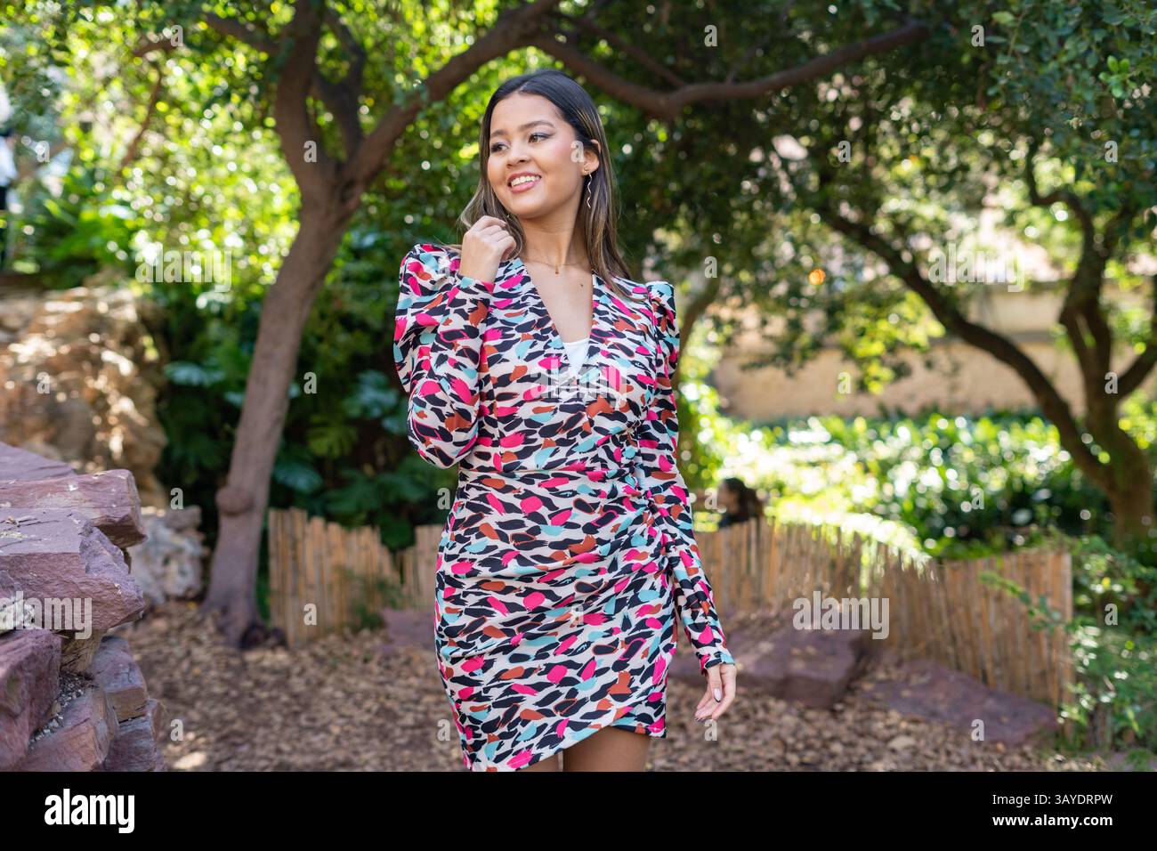 A stylish woman poses gracefully in a vibrant, eyecatching dress while ...