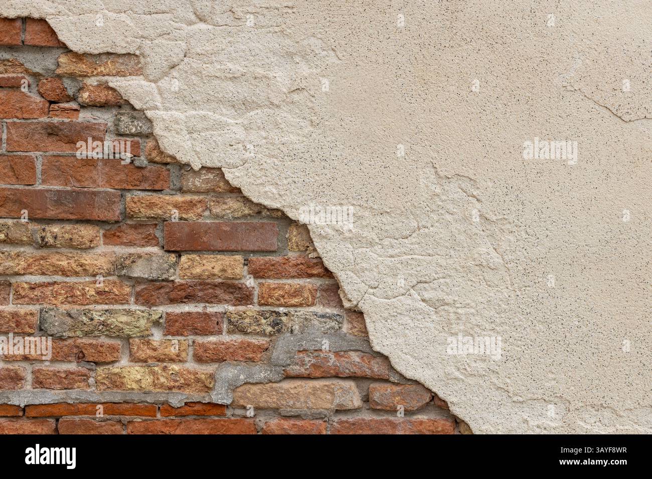 Exposed Brick Wall with Crumbling Plaster Stock Photo