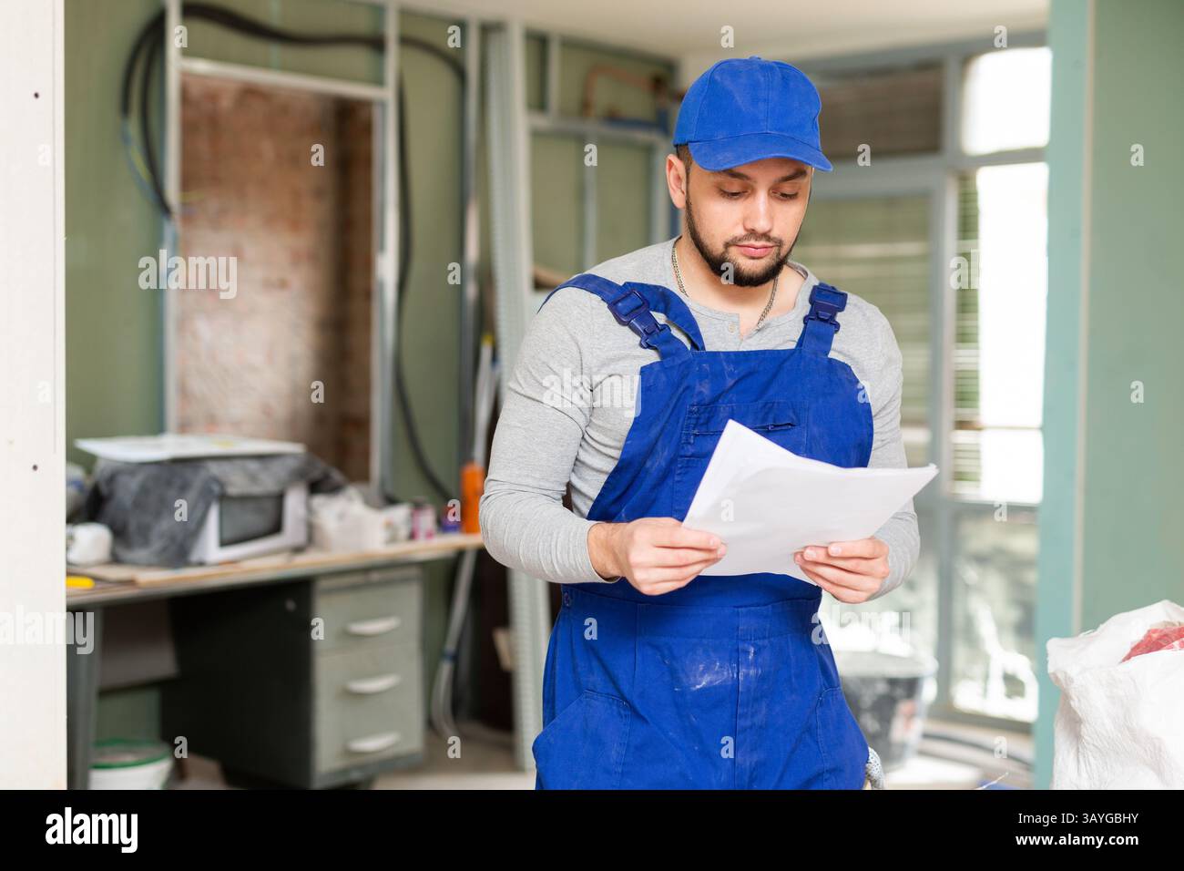 Foreman reading papers on indoor construction site Stock Photo