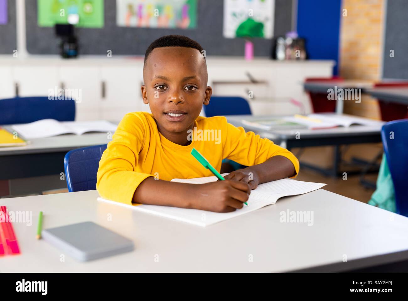 African American child writing in open notebook at school desk, using ...