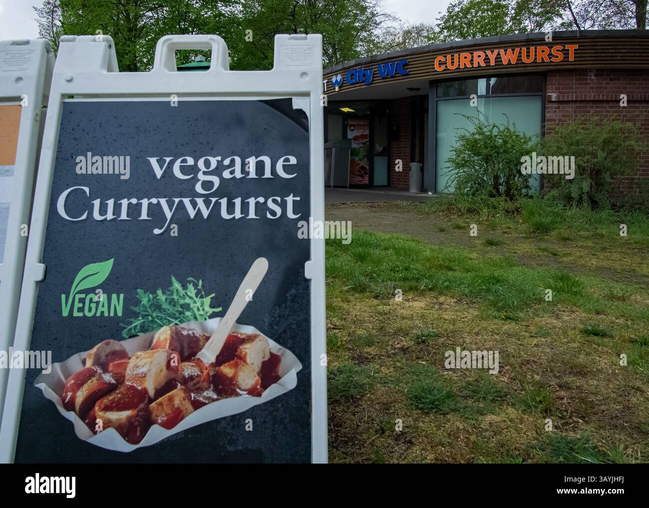 Vegan currywurst signboard with a takeaway snack stand in the background near Alexanderplatz, central Berlin, Germany. Stock Photo