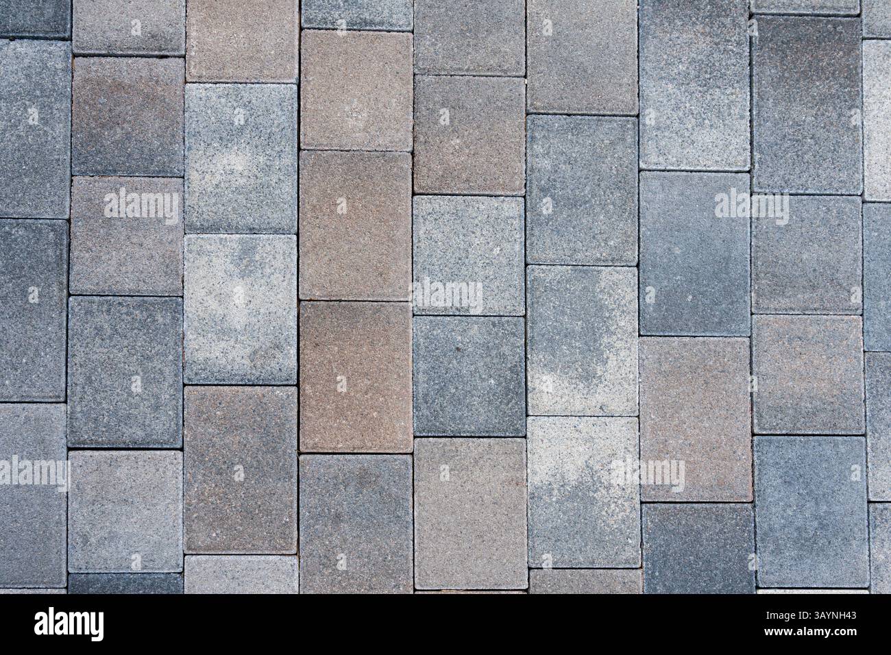 Close-up view of a wall or pavement made of rectangular stone pavers or bricks in varying shades of gray, red, and brown. The rough texture and repeat Stock Photo
