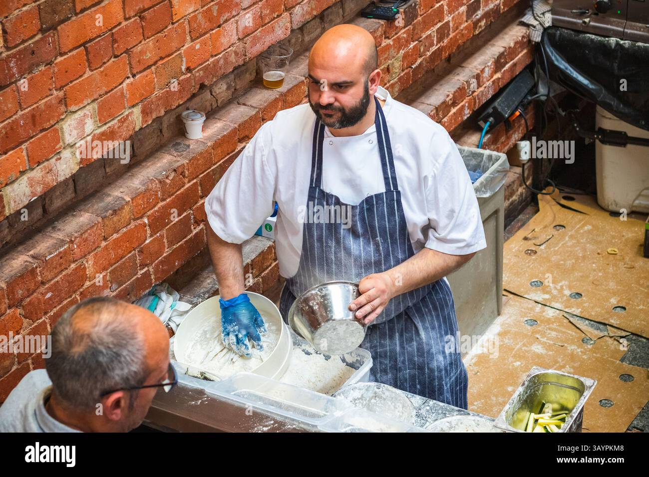 London, UK - 18 October, 2024 - Food vendors battering and breading fish at Brick Lane market Stock Photo
