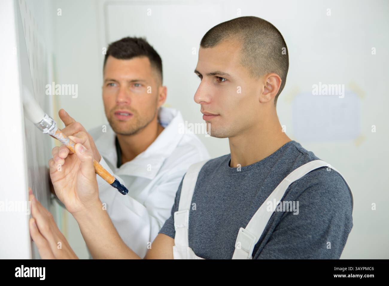 apprentices learning how to paint with a thick brush Stock Photo