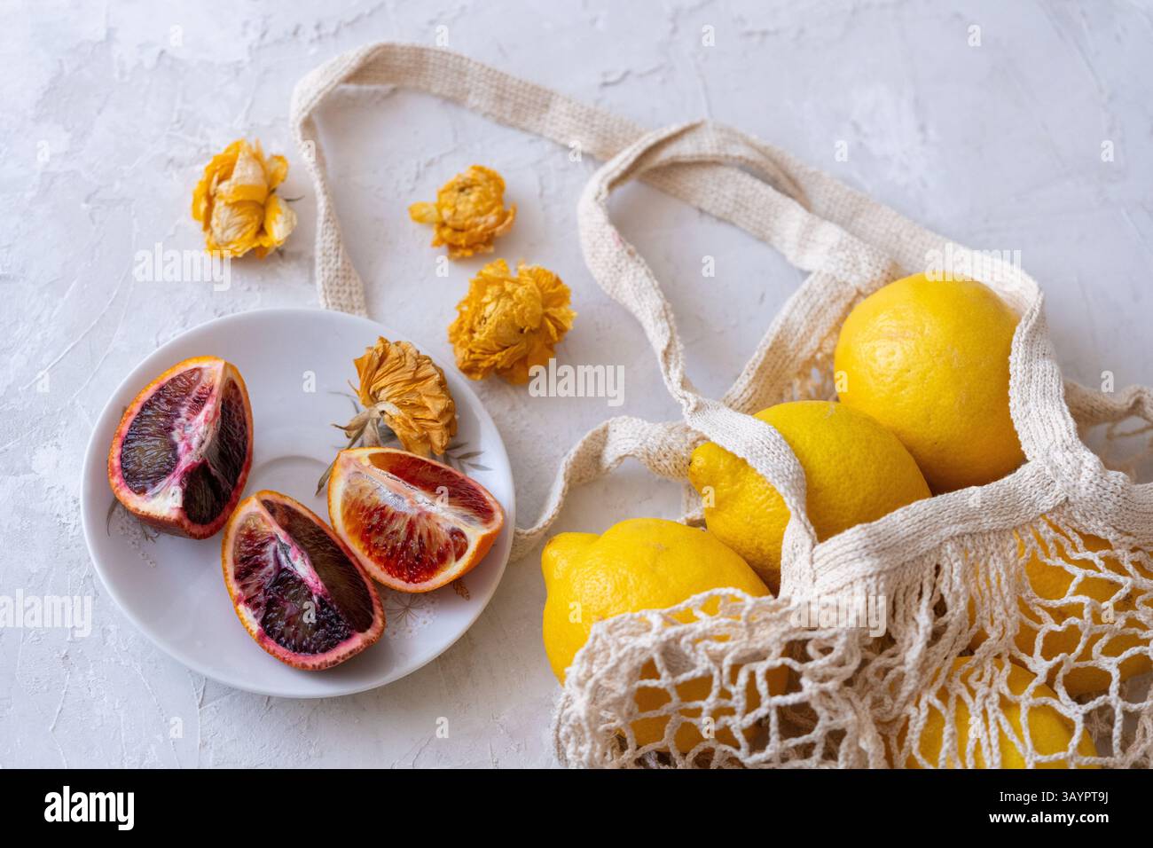 Lemons and oranges in a string bag on a white background Stock Photo