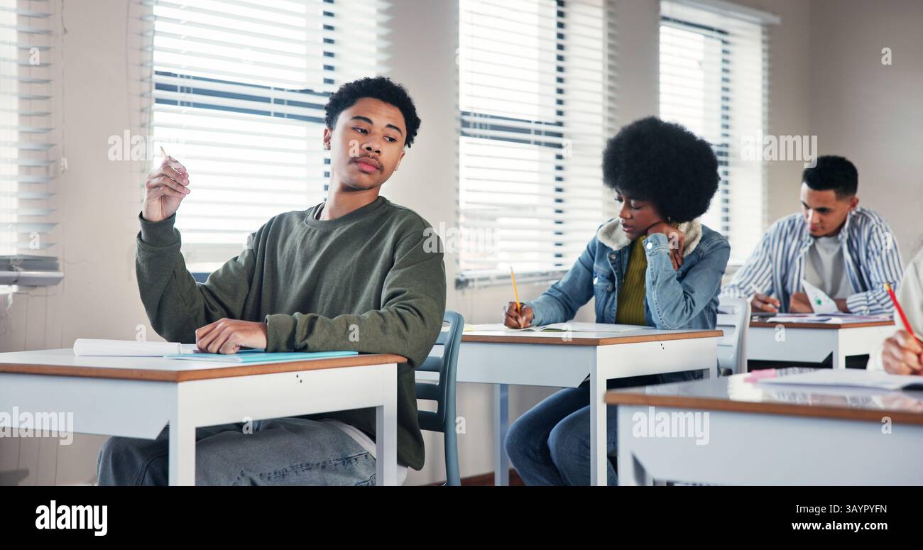 Education, student and cheating with test in classroom for exam confusion, copy answer and scholarship risk. High school, boy and assessment fraud Stock Photo