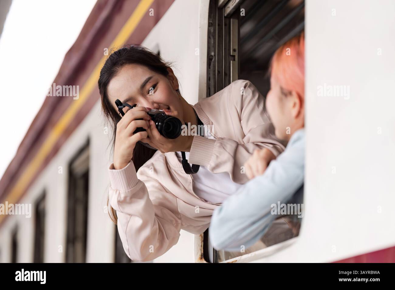 Friends Catching Train Capturing Moments and Joy. A young woman taking photos of her friend ...