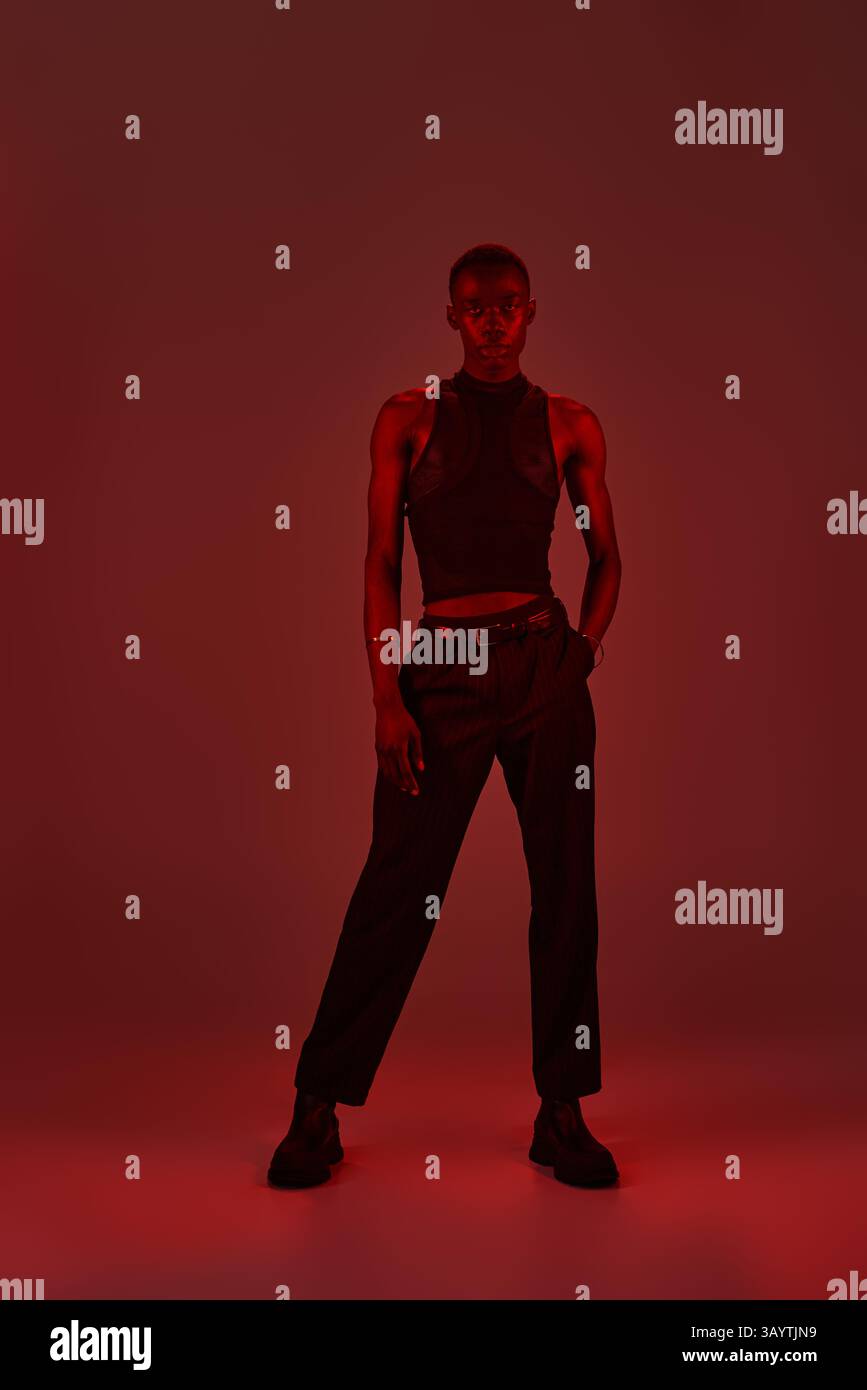 A young african american man displays his stylish outfit against a bold ...