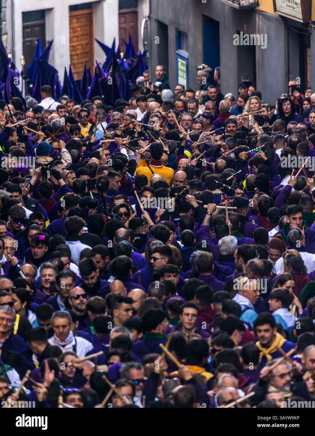 Turbas de Cuenca in purple robes make a deafening noise with their drums (tambores) and tin trumpets (clarines) at the head of the Camino del Calvario procession, which passes through Cuenca on Good Friday. Many people hit each other with crossed drumsticks and create the sound known as palilladas. Plaza Mayor, Cuenca, Castilla-La Mancha, Spain Stock Photo