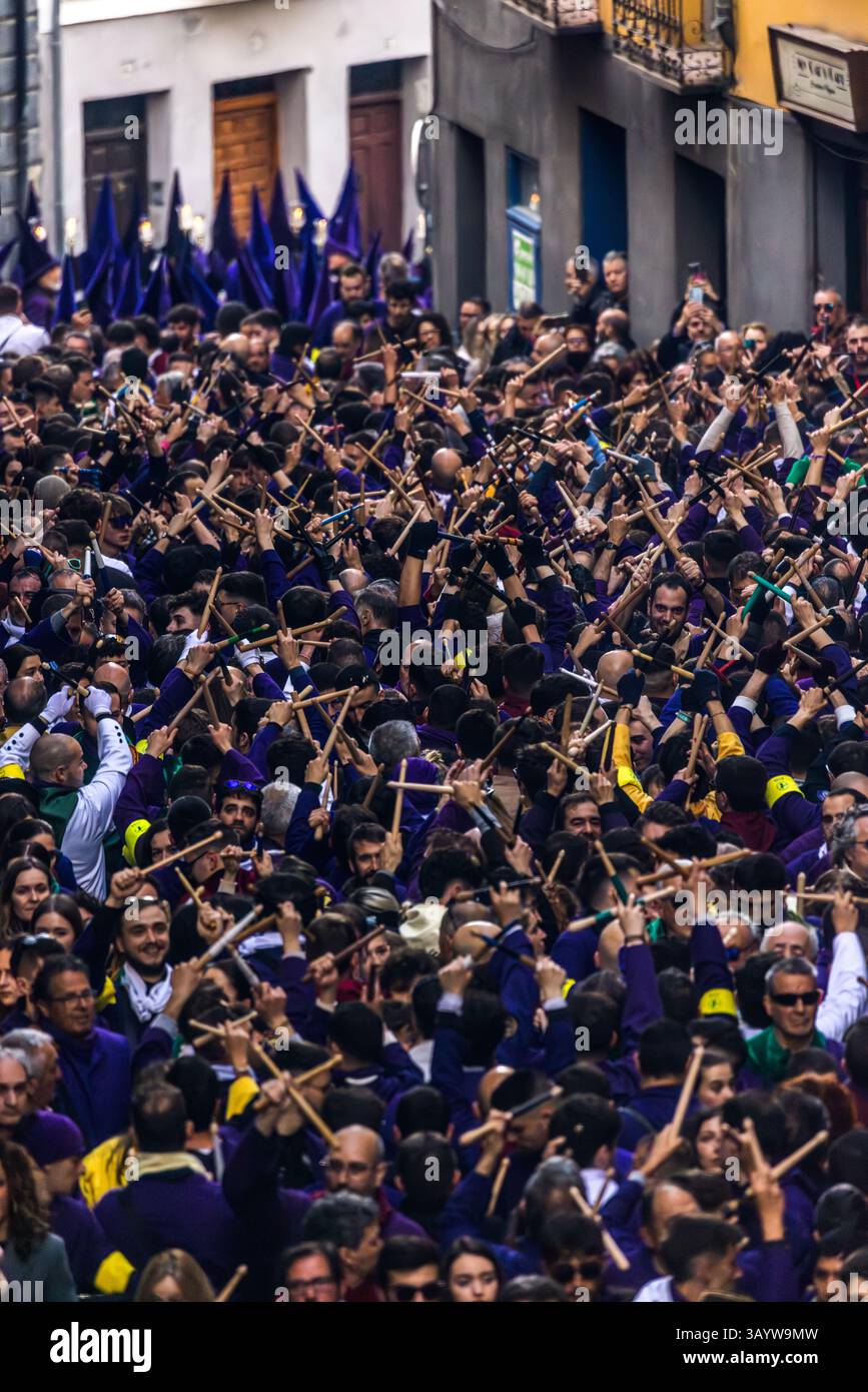 Turbas de Cuenca in purple robes make a deafening noise with their drums (tambores) and tin trumpets (clarines) at the head of the Camino del Calvario procession, which passes through Cuenca on Good Friday. Many people hit each other with crossed drumsticks and create the sound known as palilladas. Plaza Mayor, Cuenca, Castilla-La Mancha, Spain Stock Photo