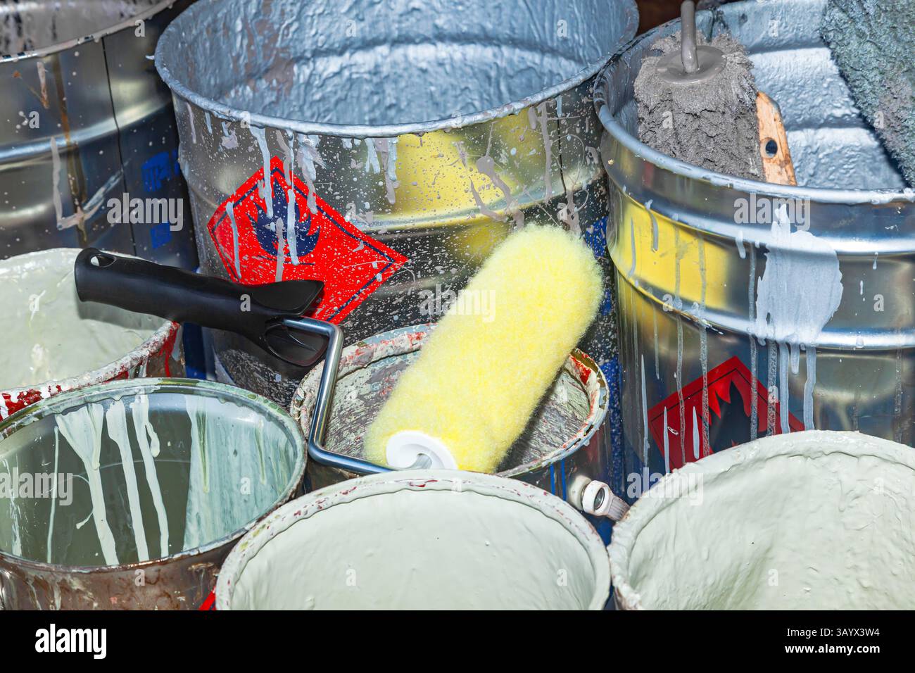 Empty paint buckets containing used rollers and brushes. Stock Photo