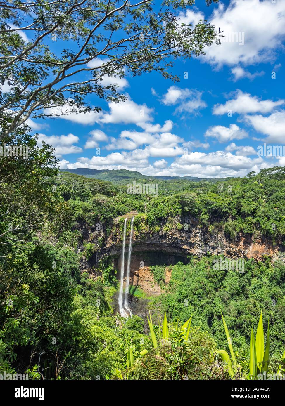 Majestic Waterfall in Lush Valley. Breathtaking Waterfall Amidst Green Mountains  Stock Photo