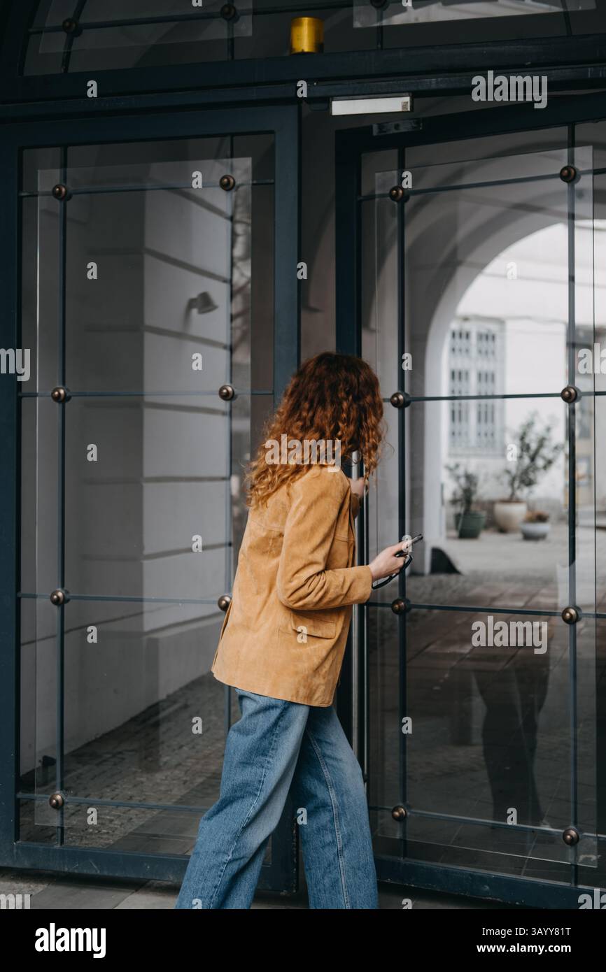 Modern woman entering smart-access workspace with mobile device. Urban flexibility, contactless tech, and digital fluidity... Stock Photo