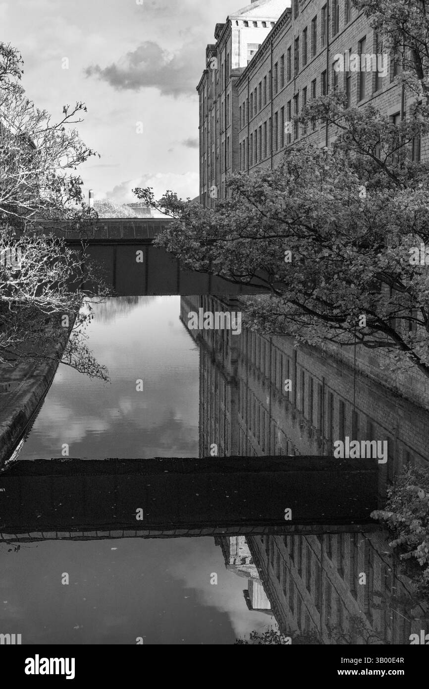 Leeds and Liverpool Canal reflects Salts Mill,Saltaire, West Yorkshire, UK. Stock Photo