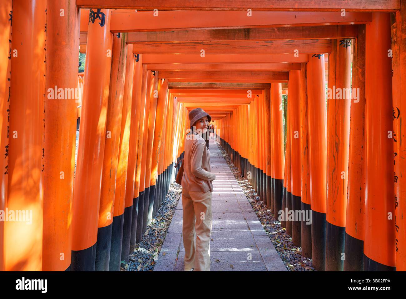 Beautiful asian woman enjoying in tunnel of vibrant red torii gates ...