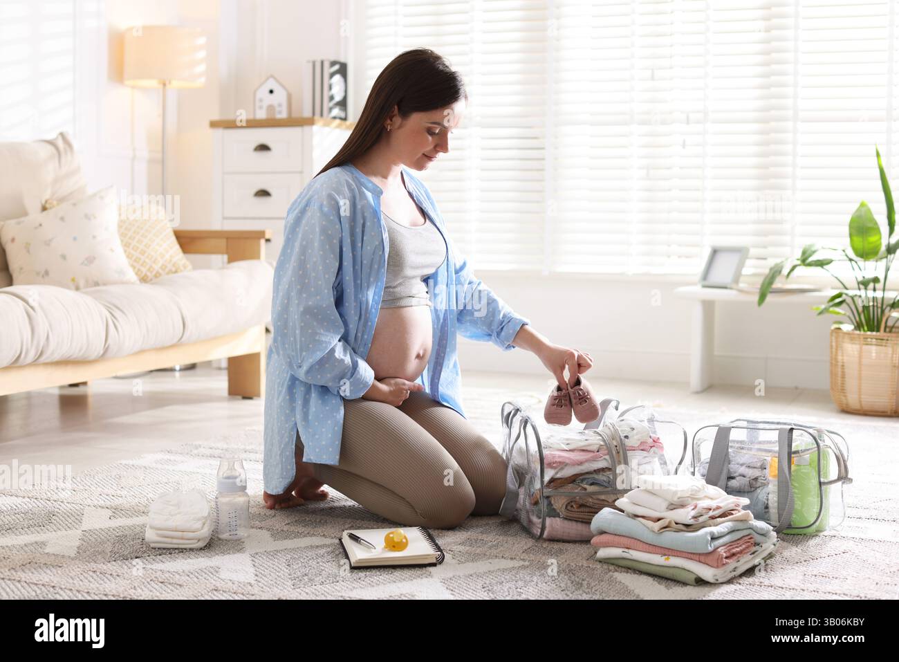 Pregnant woman packing baby stuff to bring into maternity hospital at ...