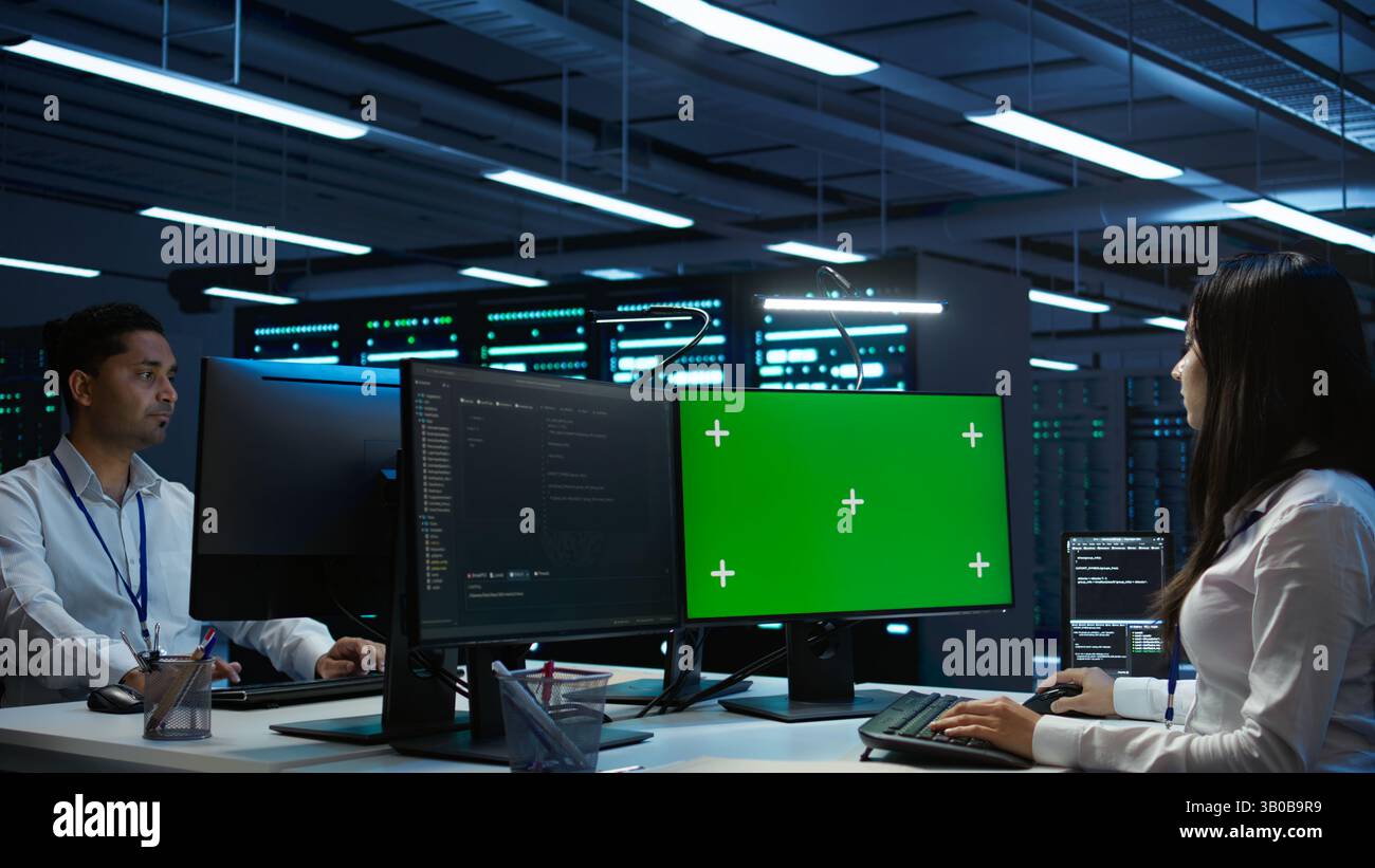 System administrator in data center installing software on green screen computer, troubleshooting issues. IT expert uses mockup PC in server hub, establishing performance benchmarks, camera B Stock Photo