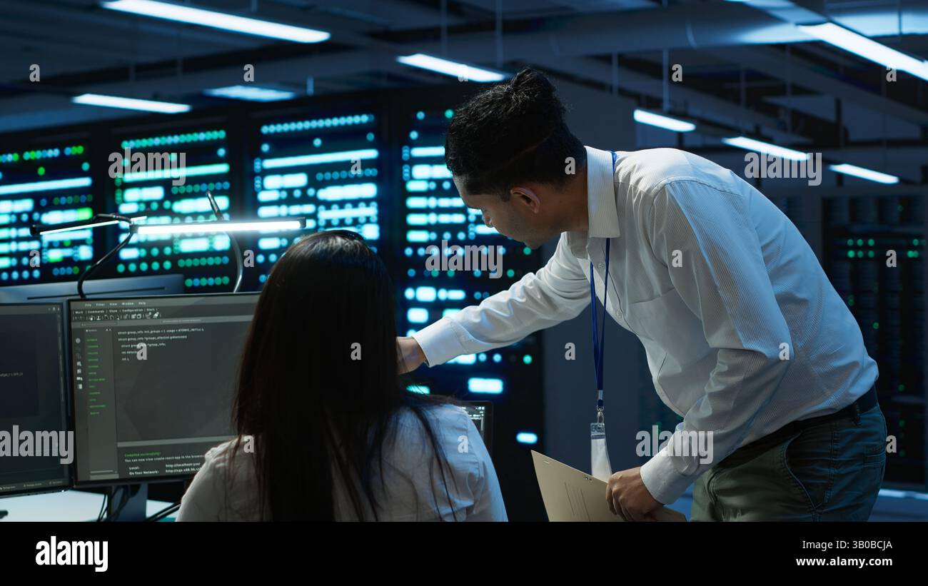 Computer scientists in data center managing and maintaining databases, ensuring data integrity and security. IT staff members updating server room systems using, camera A Stock Photo