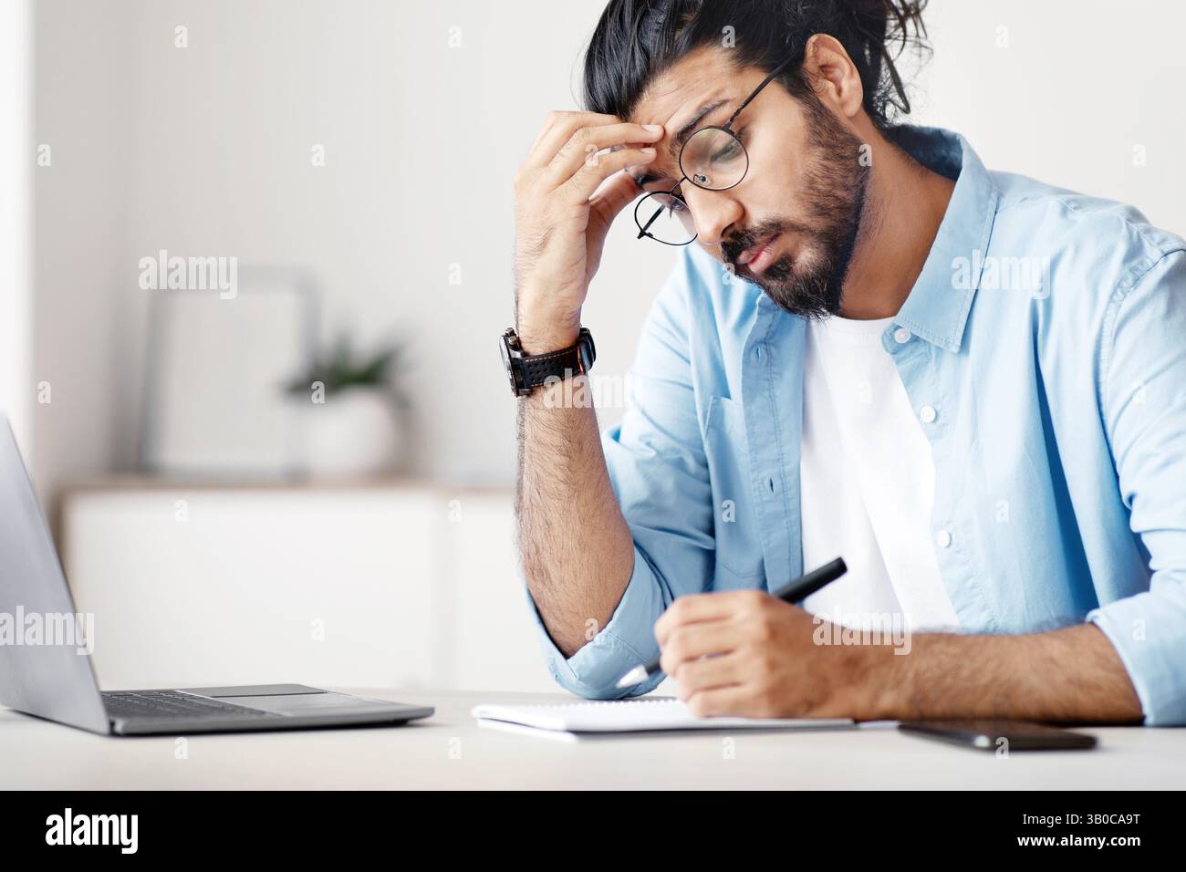 Freelancer Guy Taking Notes To Notepad While Working At Home Office Stock Photo