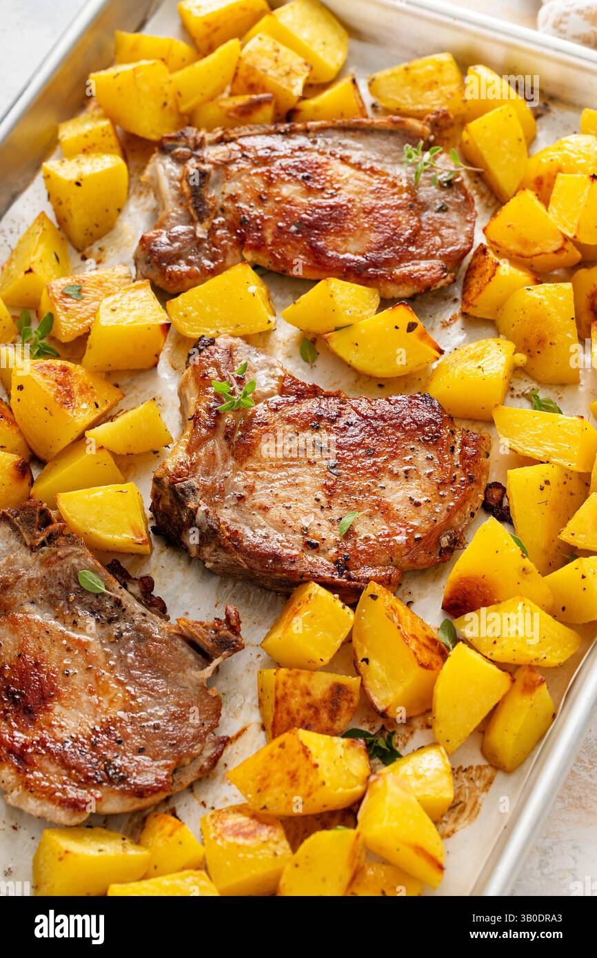Pork chops and potatoes on a sheet pan oven roasted with herbs and spices for an easy dinner Stock Photo