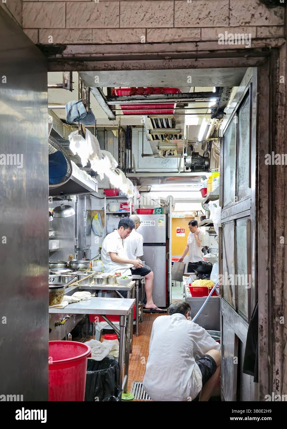 Cooks resting in the kitchen of a small restaurant before opening hours. Photo taken in Wan Chai, Hong Kong. - Smartphone Captured Stock Image