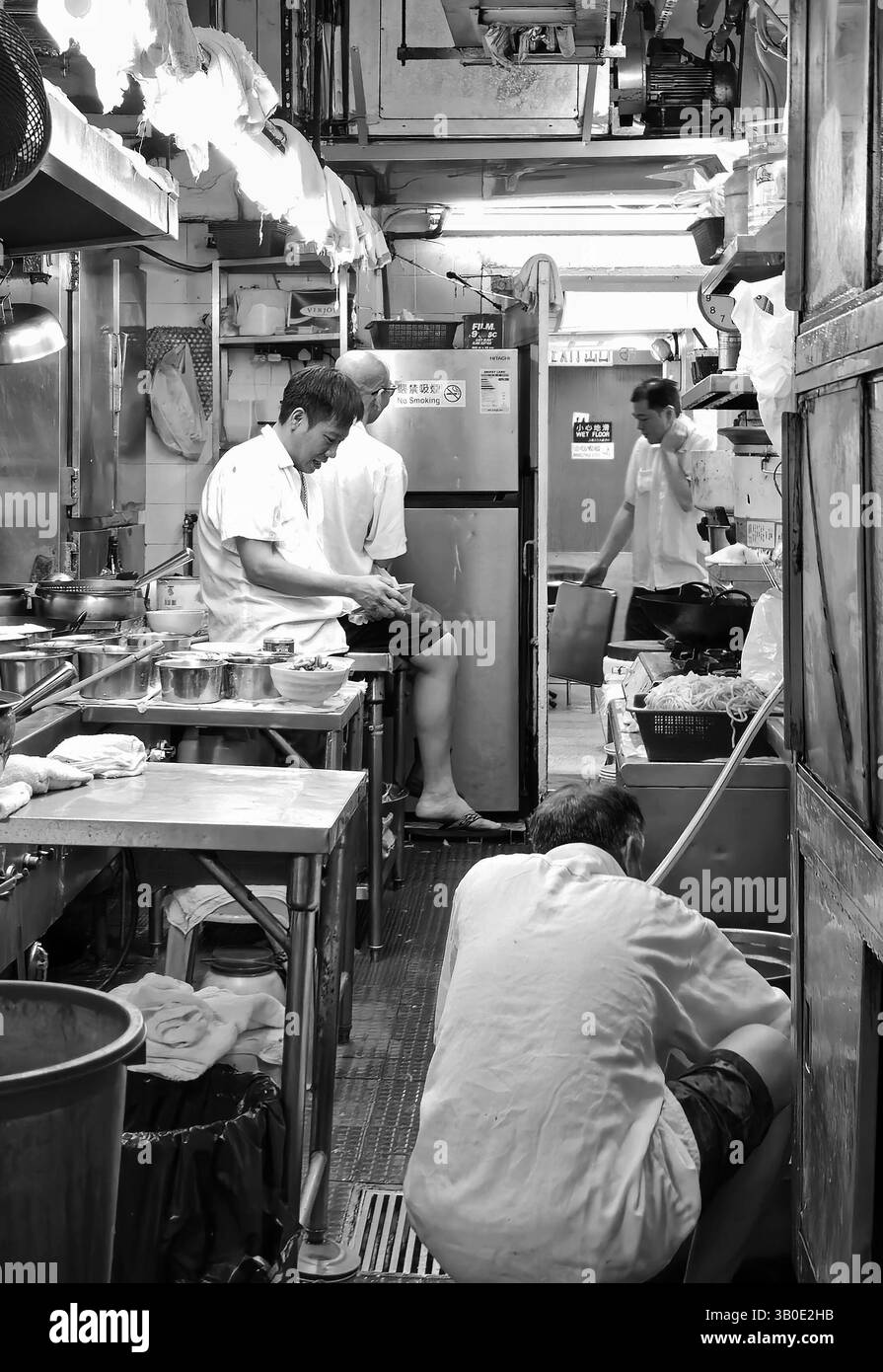 Cooks resting in the kitchen of a small restaurant before opening hours. Photo taken in Wan Chai, Hong Kong. - Smartphone Captured Stock Image