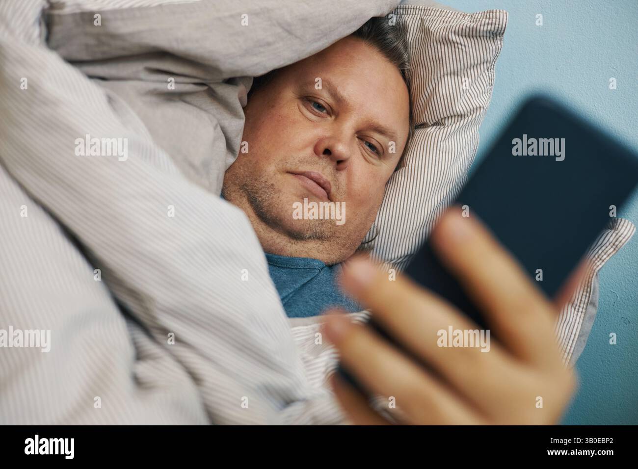 Relaxing in Bed While Using Smartphone Device Stock Photo