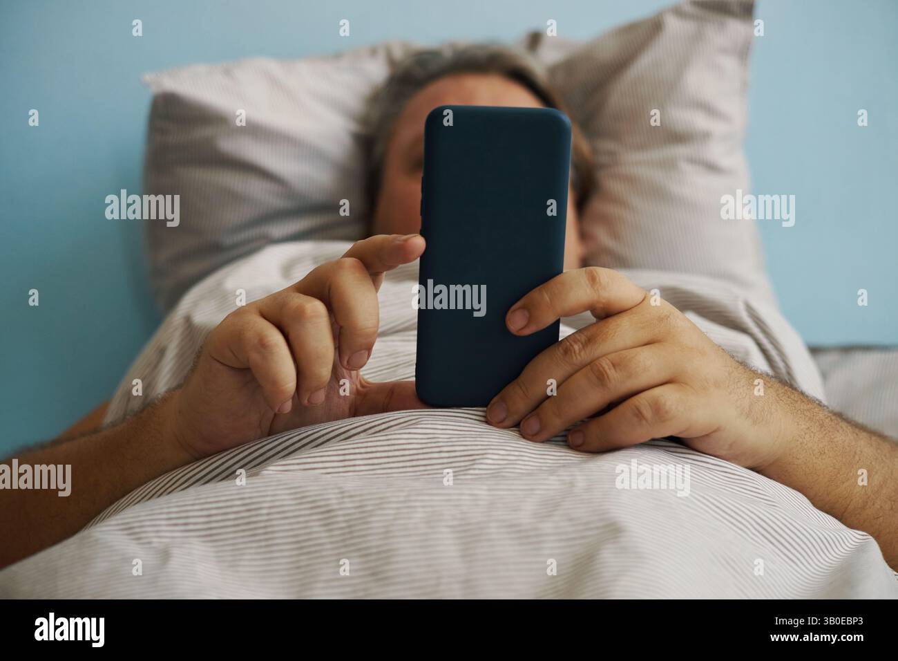 Relaxing in Bed While Using Smartphone Device Stock Photo