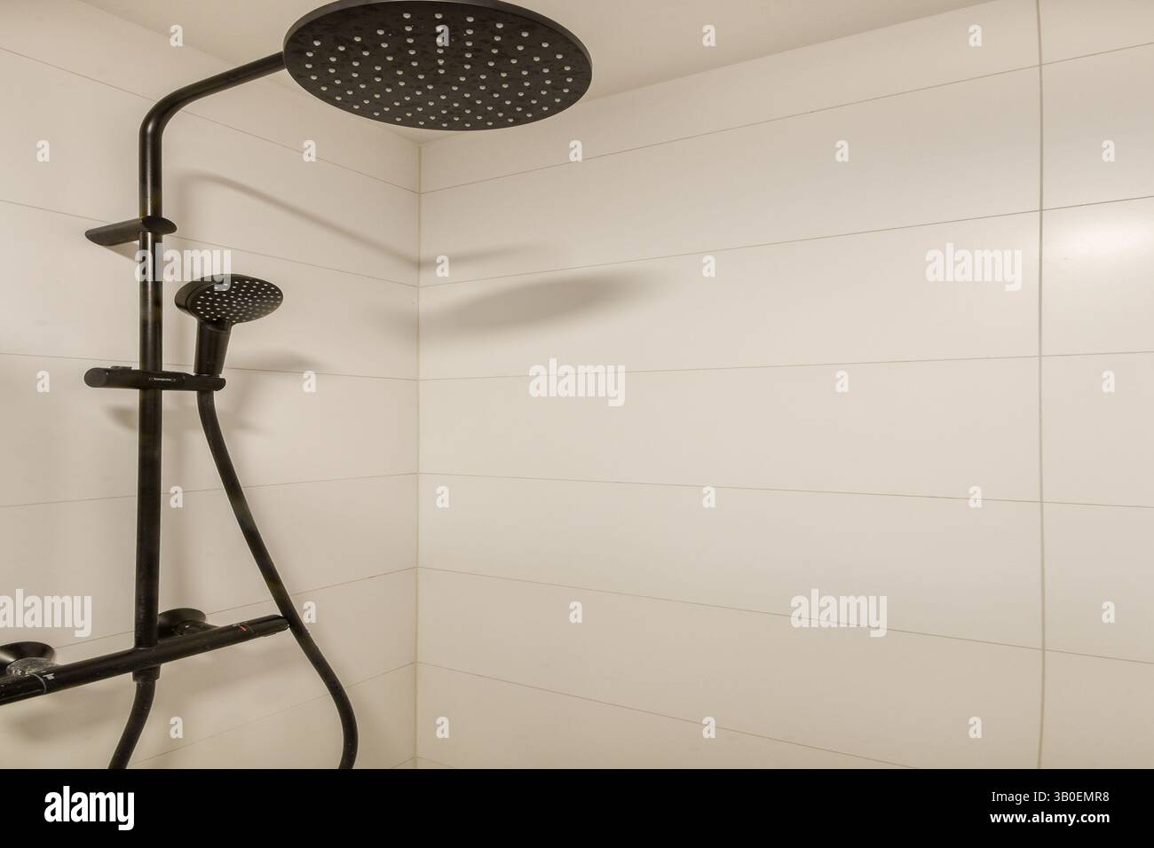 Stylish black shower fixture against clean, white tiled wall creates a ...