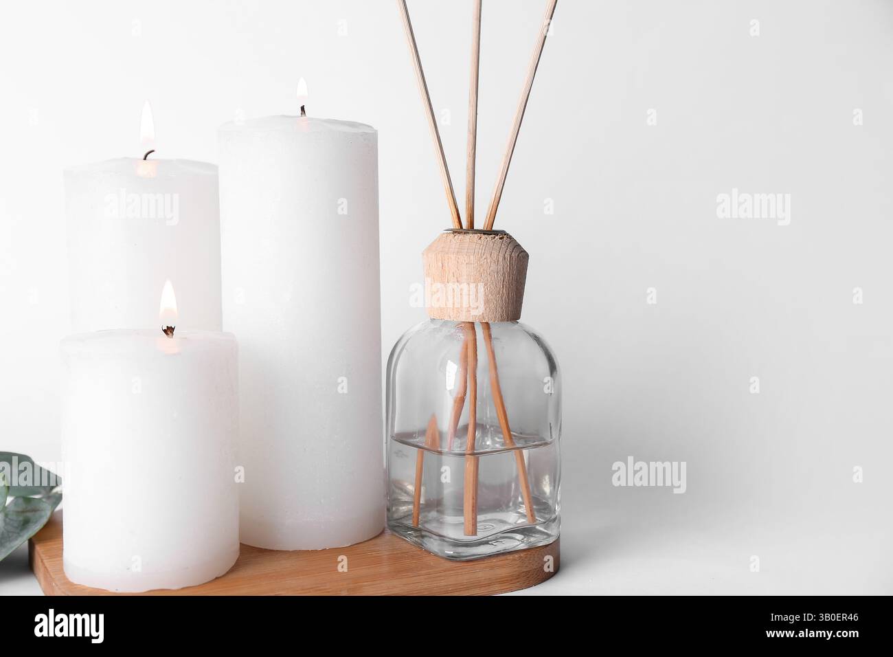 Burning candles with reed diffuser on white background Stock Photo