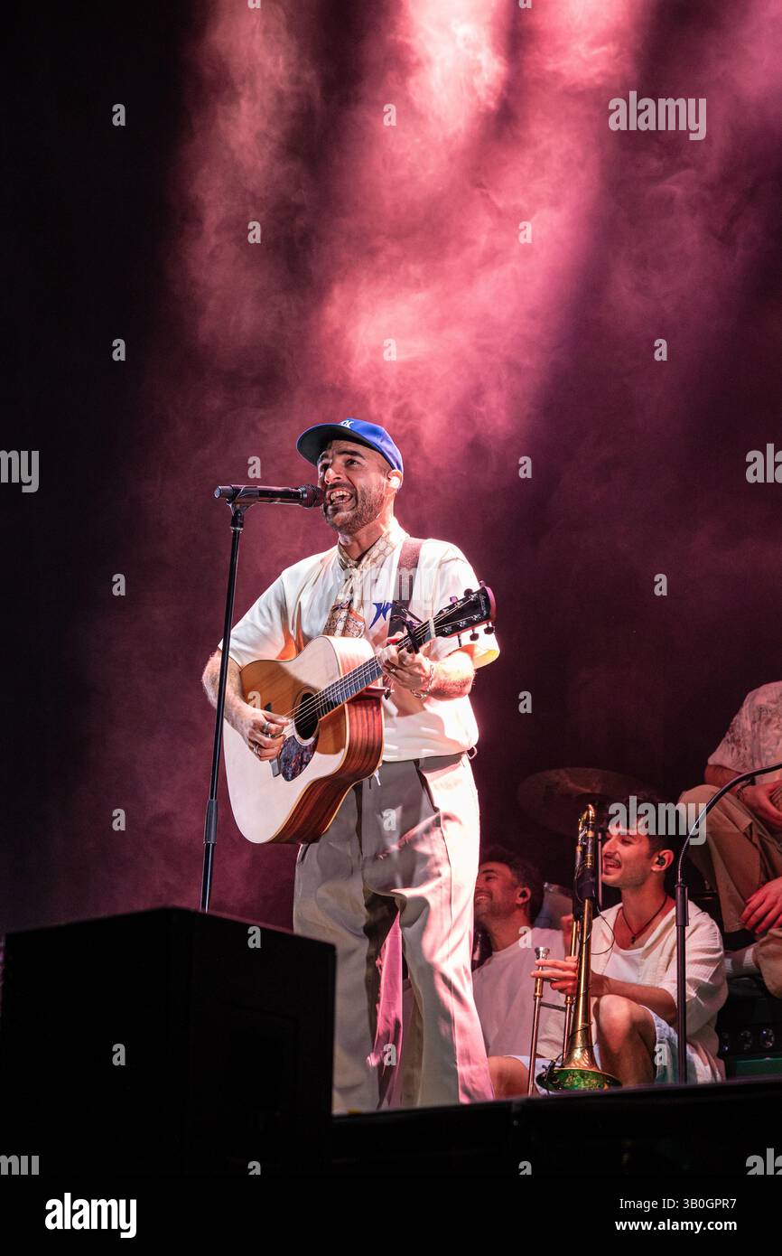 Nil Moliner performing live with acoustic guitar under pink stage ...