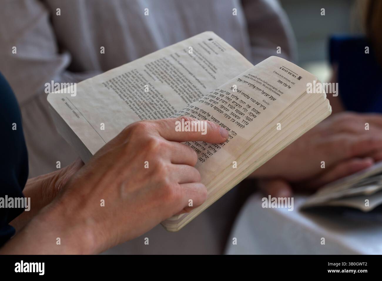 A man holds a Jewish prayer book or siddur while reciting the Hebrew