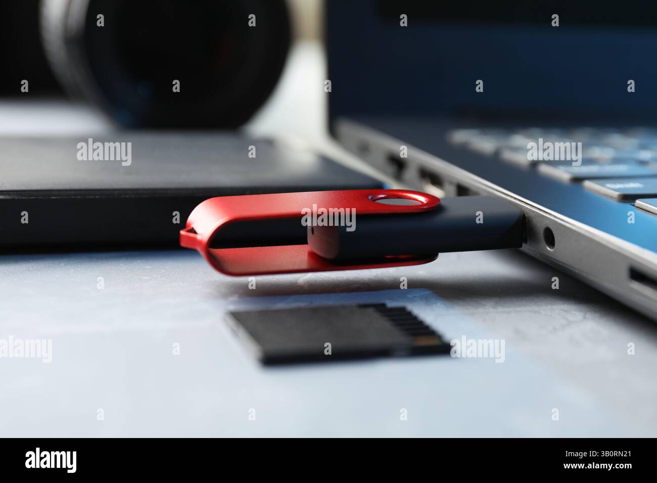 Flash drive connected to laptop, SD memory card and external hard disk on gray table, closeup Stock Photo
