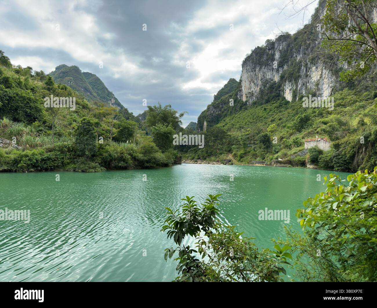 The turquoise lake reflects the beauty of the surrounding mountains and sky in a serene landscape. - Smartphone Captured Stock Image