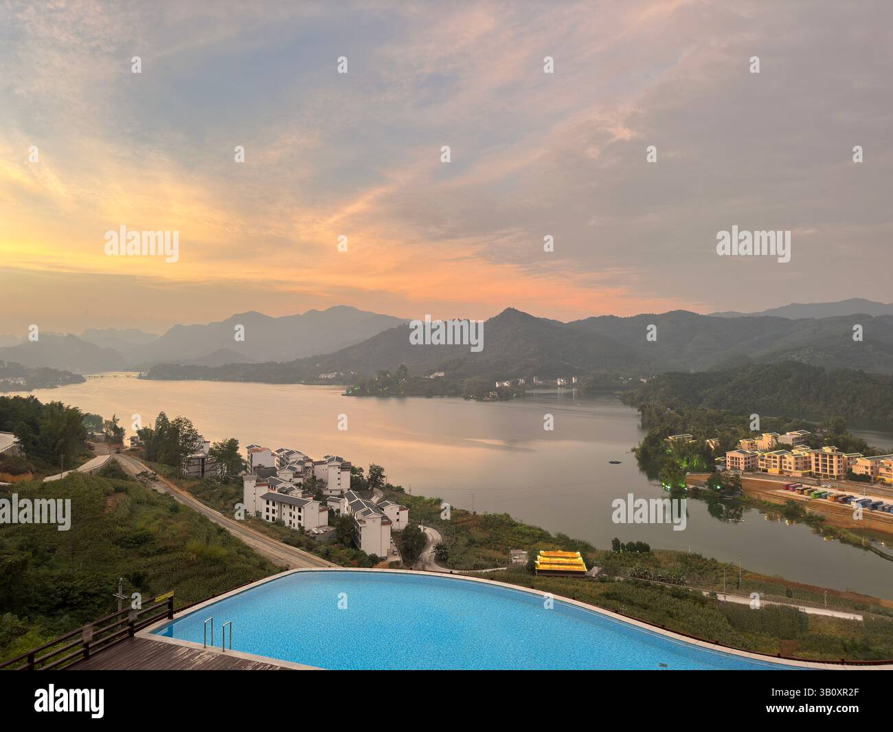 A stunning sunset paints the sky over a tranquil lake and mountain range in Guangxi, China. - Smartphone Captured Stock Image
