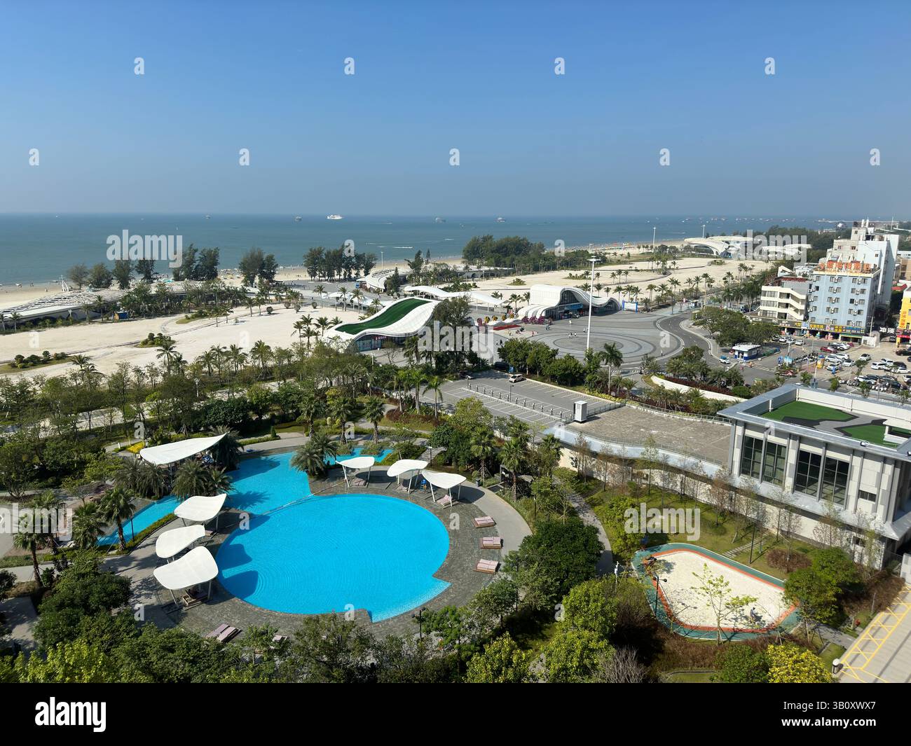 Scenic aerial view of a resort featuring a stunning pool, beach, and clear blue sky. - Smartphone Captured Stock Image
