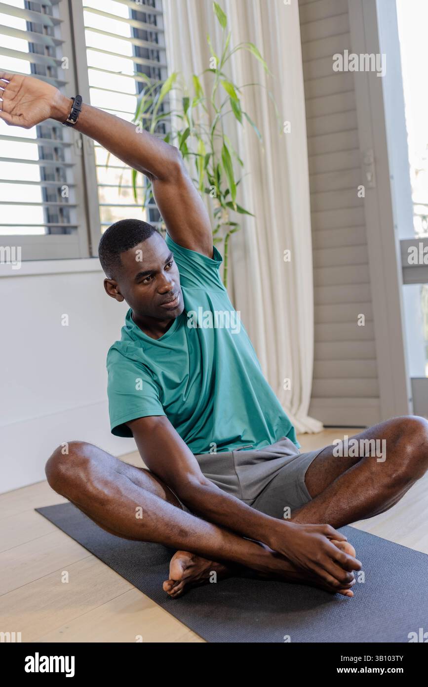 Stretching African American man reaching right foot in home studio ...