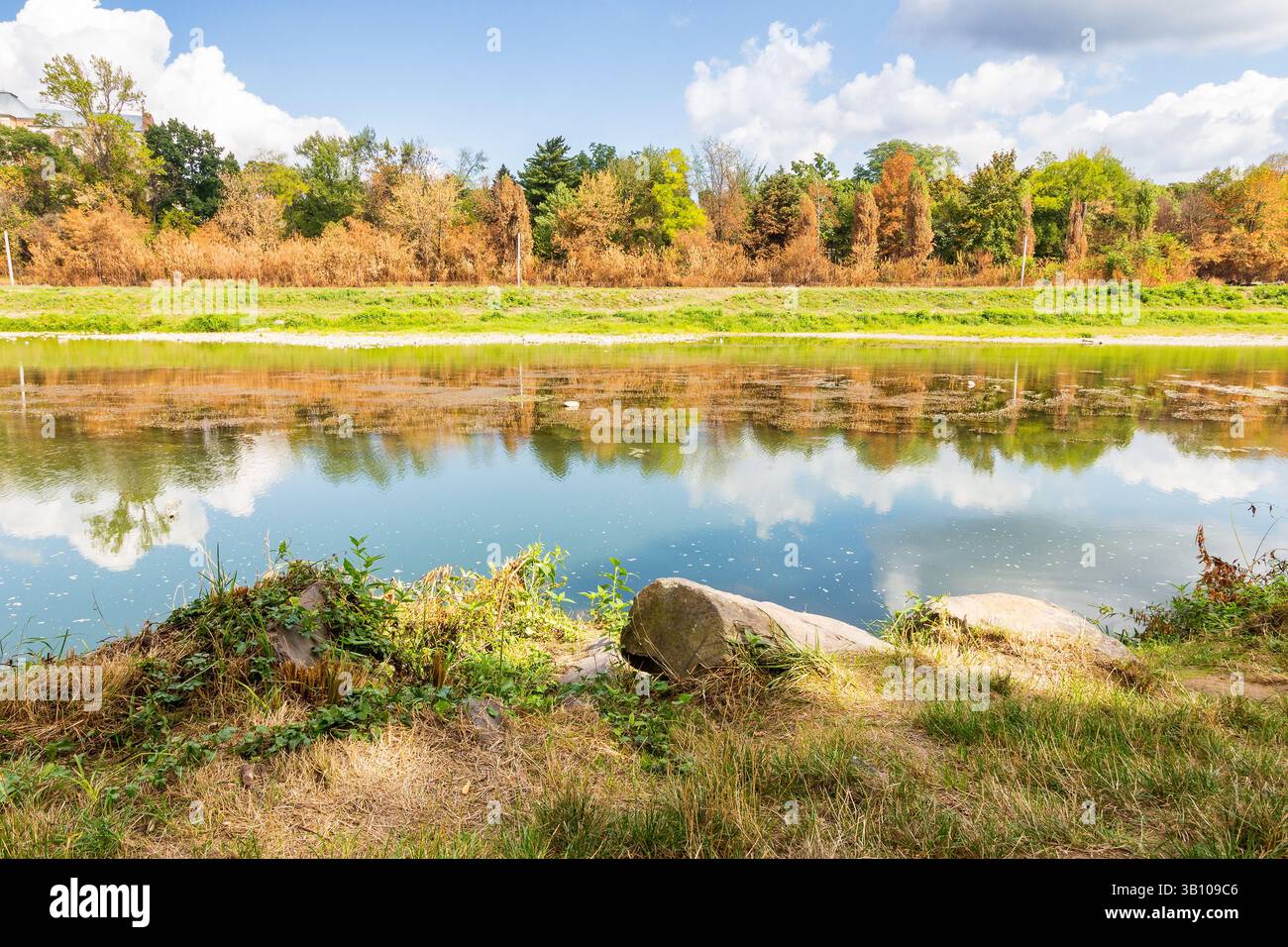 uzh river in autumn. sunny weather. trees on the shore and clouds on the sky reflecting in the calm water. urban landscape Stock Photo