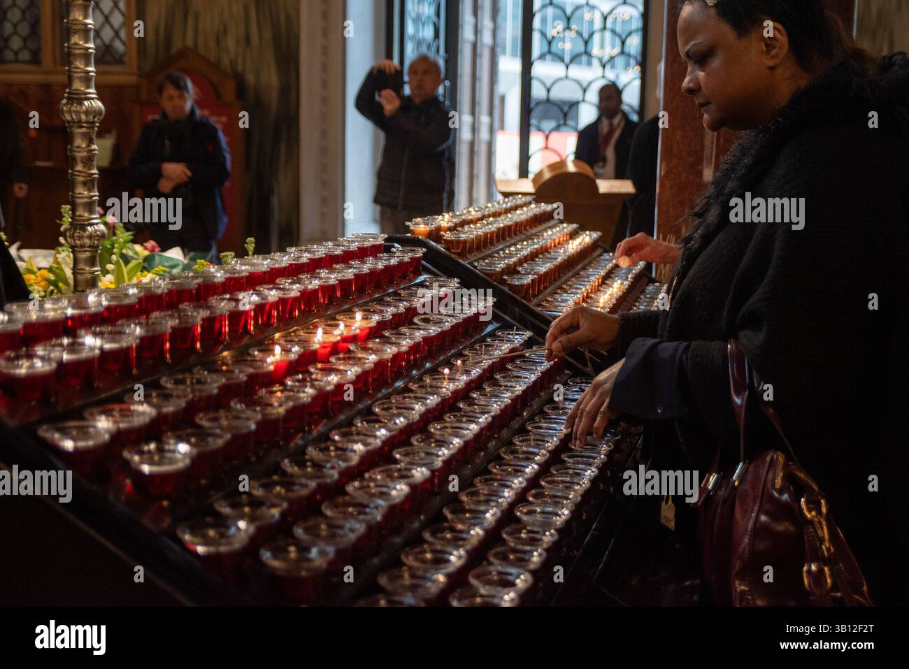London, UK. 24th Apr, 2025. A female believer lights up a tea candle to pay respect to Pope Francis at the Westminster Cathedral. The head of the Catholic Church, Pope Francis died on Easter Monday on 21st of April 2025 at the age of 88 in Vatican. Since Monday thousands of believers are going daily to the Westminster Cathedral in London to pay respect to him. Credit: SOPA Images Limited/Alamy Live News Stock Photo