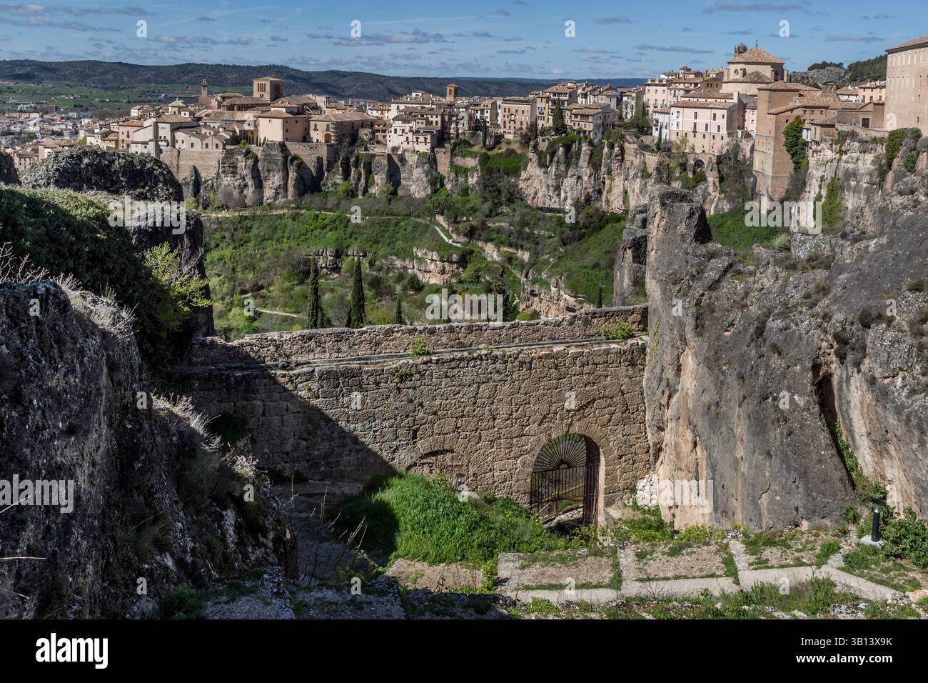 View of the city of Cuenca in Spain with a rock face and an old wall in the foreground that bordered the property of the poet Federico Muelas. Calle Larga, Cuenca, Castilla-La Mancha, Spain Stock Photo