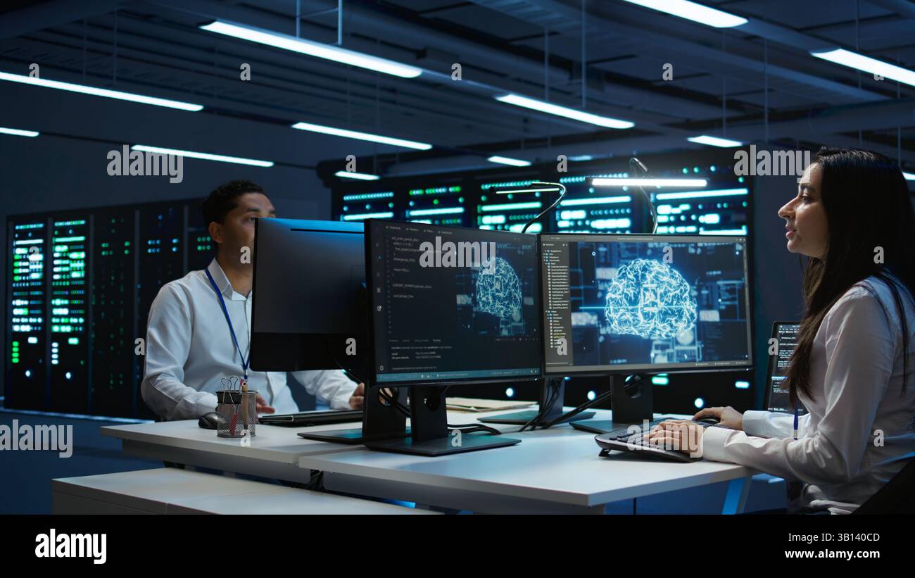 Team of engineers using AI tech on computer to do checkup in server room. Data center workers using artificial intelligence technology to process datasets for training, camera B Stock Photo