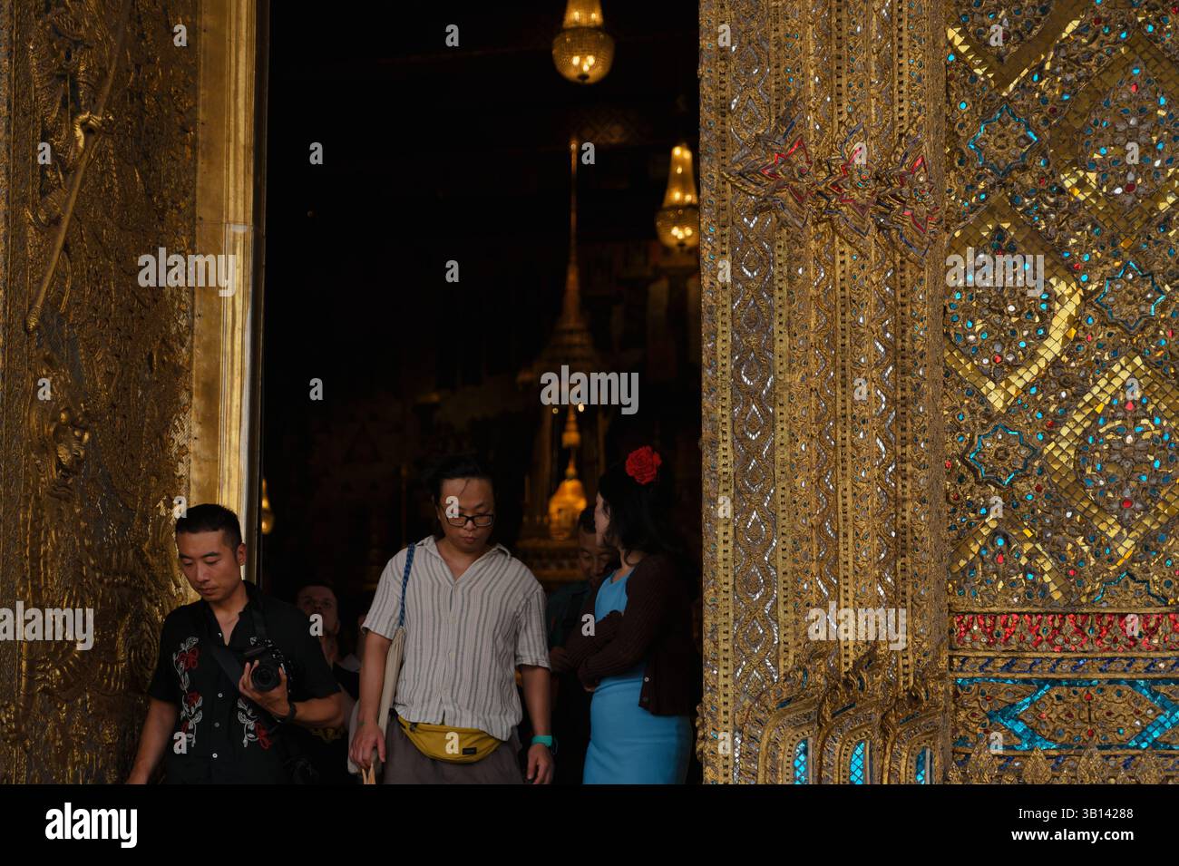 Visitors emerge from the richly ornamented entrance of Wat Phra Kaew Stock Photo